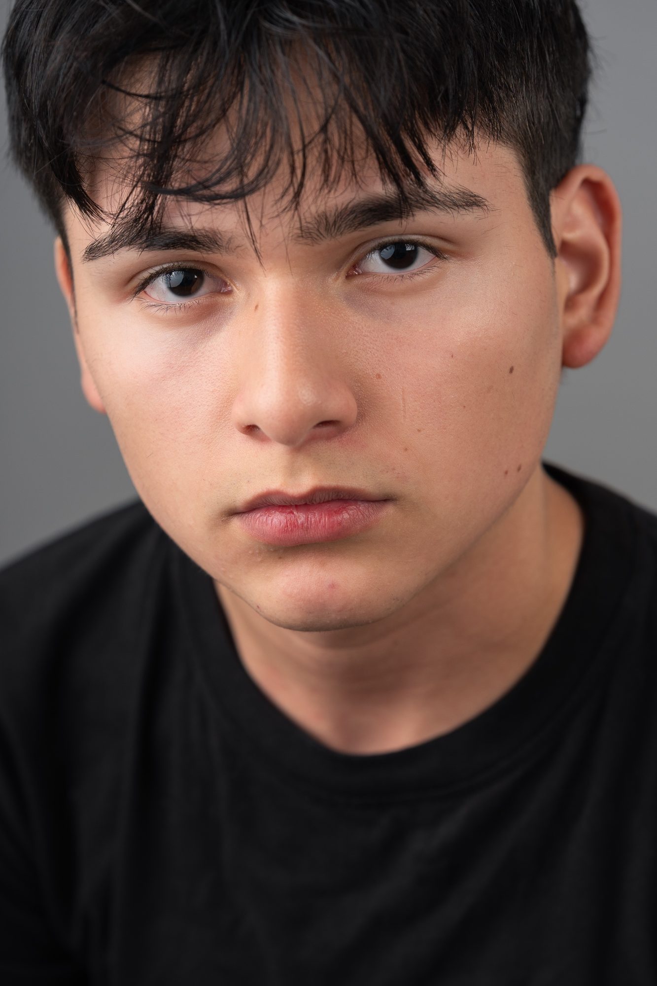 Senior studio headshot, dark hair, black t-shirt, gray background